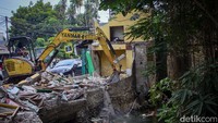 Alat berat dikerahkan membereskan puing-puing bangunan.  