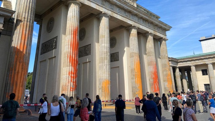 Protes Bahan Bakar Fosil, Gerbang Bersejarah di Jerman Dilumuri Cat People walk in front of the Brandenburg Gate after Last Generation (