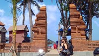 Seorang wisatawan melintas di depan salah satu gapura pintu masuk Pantai Kuta, Badung, Bali. Pemerintah Kabupaten Badung mengganti tembok pembatas dan gapura di Pantai Samigita dari bata palimanan yang berwarna putih menjadi bata merah.