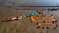 Sejumlah masyarakat dan nelayan yang tergabung dalam komunitas pegiat lingkungan Lingkar Juang Karimunjawa bersama aktivis lingkungan Greenpeace Indonesia dan lintas komunitas pecinta alam menggunakan kayak sambil membentangkan spanduk saat aksi SaveKarimunjawa di tepi pantai yang tercemar limbah tambak udang di Desa Kemujan, kepulauan wisata bahari Karimunjawa, Jepara, Jawa Tengah, Selasa (19/9/2023).  