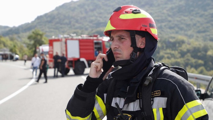Bus Masuk Jurang di Montenegro, WN Inggris Tewas A rescue worker talks on the phone while police investigate the scene of a fatal road accident where a bus crashed into a ravine near Cetinje, Montenegro, September 19, 2023. REUTERS/Stevo Vasiljevic