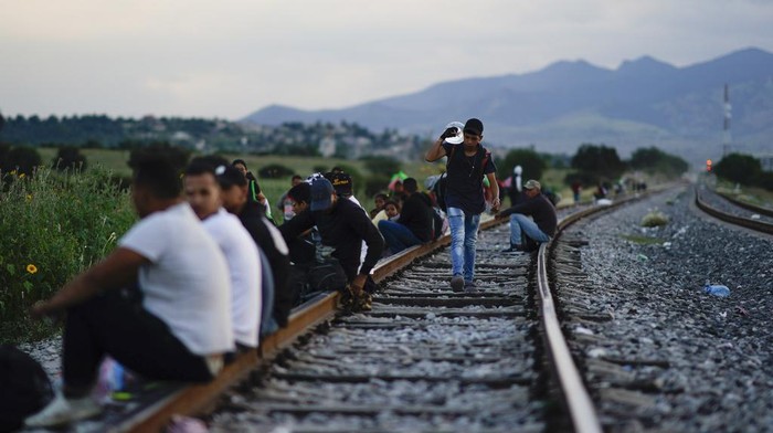 Migrants watch a train go past as they wait along the train tracks hoping to board a freight train heading north, one that stops long enough so they can hop on, in Huehuetoca, Mexico, Sept. 19, 2023. Ferromex, Mexico's largest railroad company announced that it was suspending operations of its cargo trains due to the massive number of migrants that are illegally hitching a ride on its trains moving north towards the U.S. border. (AP Photo/Eduardo Verdugo)