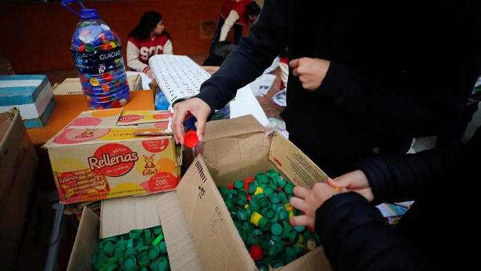 Art teacher Sebastian Ramirez, 41, waves with his students next to the mural they made with plastic bottle caps depicting Argentina's soccer superstar Lionel Messi, nine months after Argentina won the soccer World Cup Qatar 2022, in Grand Bourg, on the outskirts of Buenos Aires, Argentina September 19, 2023. REUTERS/Agustin Marcarian