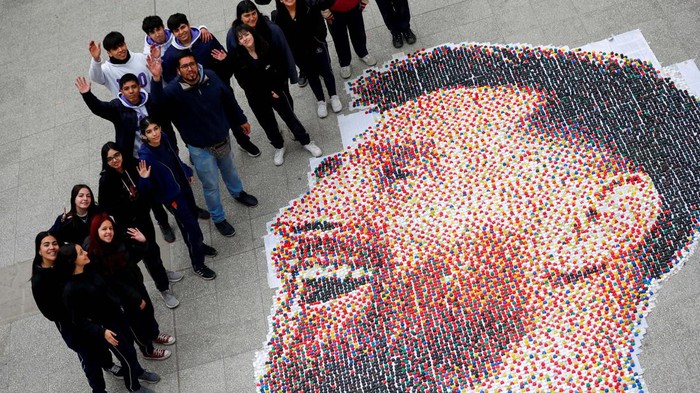 Art teacher Sebastian Ramirez, 41, waves with his students next to the mural they made with plastic bottle caps depicting Argentina's soccer superstar Lionel Messi, nine months after Argentina won the soccer World Cup Qatar 2022, in Grand Bourg, on the outskirts of Buenos Aires, Argentina September 19, 2023. REUTERS/Agustin Marcarian