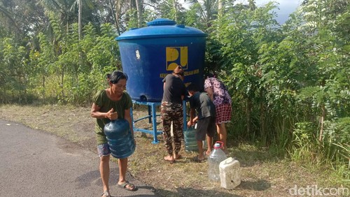 Warga mengambil air dari tempat penampungan yang didistribusikan PDAM.