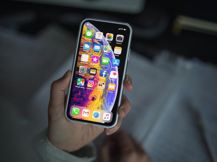 Celje, Slovenia - October 07, 2018: Woman holding new iPhone XS smartphone (with protective VRS design case, 5.8 inch Retina display, silver color version with 256 GB memory) in her hand over the note pad.