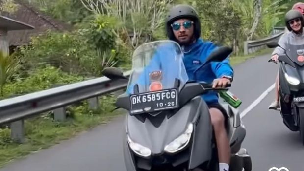 Tangkapan layar bule naik motor sambil minum bir.
