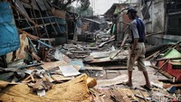 Warga berjalan di puing-puing bangunan yang ditertibkan.  