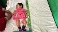 Tampak seorang bayi diukur tinggi badan di dalam ruangan. 