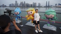 Para perempuan berfoto di depan maskot Asian Games ke-19 yang dipajang di tepi sungai di Hangzhou. Panitia mengatakan lebih dari 12.000 orang akan diikutsertakan saat upacara pembukaan berlangsung Sabtu, 23 September di kota Hangzhou. AP/Vincent Thian