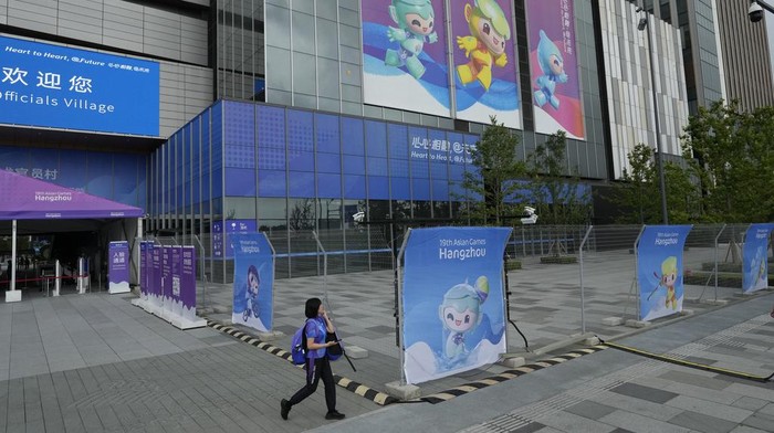 A woman past by displays of the Asian Game mascots near the officials village at the 19th Asian Games in Hangzhou, China, Wednesday, Sept. 20, 2023. (AP Photo/Ng Han Guan)