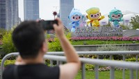 Seorang pria memotret maskot Asian Games ke-19 di luar Hangzhou Olympic Sports Centre Stadium. Ini adalah acara internasional multi-olahraga terbesar di negara ini sejak pembatasan pandemi dicabut sekitar sembilan bulan lalu. AP/Vincent Thian