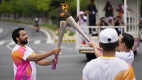 Seorang pembawa obor melewati api saat estafet obor Asian Games ke-19 di Hangzhou. Ini adalah acara internasional multi-olahraga terbesar di negara ini sejak pembatasan pandemi dicabut sekitar sembilan bulan lalu.  
