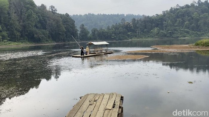 Wisatawan menaiki perahu saat danau Situ Gunung surut