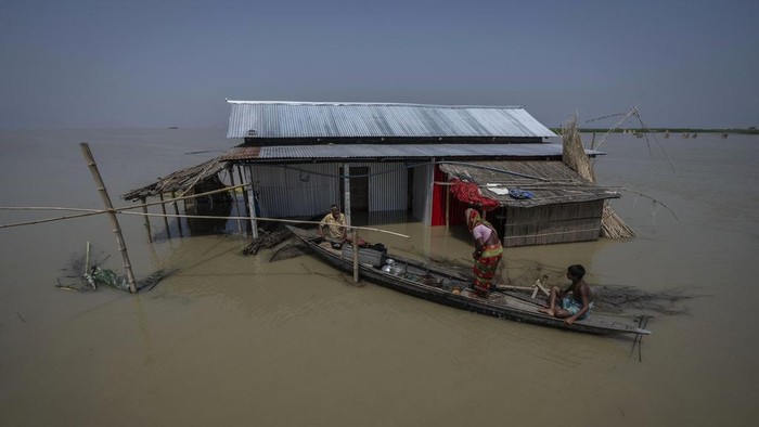 A flood victim sits on a submerged boat dock in Sandahkhaiti, a floating island village in the Brahmaputra River in Morigaon district, Assam, India, Wednesday, Aug. 30, 2023. (AP Photo/Anupam Nath)