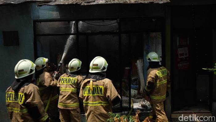 Petugas pemadam kebakaran memadamkan api di Rusun Petamburan, Jakarta. Tampak ruangan yang terbakar adalah tempat laundry pakaian.