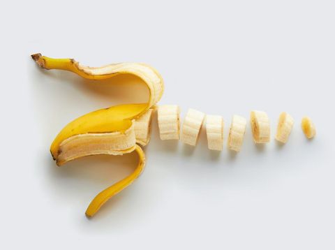 A peeled and sliced single banana isolated on a natural colored background.