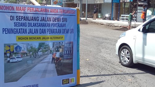Papan pengumuman proyek peningkatan jalan dan penataan Jalan Dewi Sri, Kuta, Badung, Bali. Arus lalu lintas dari arah utara ke selatan di jalan tersebut akan dialihkan selama lima hari mulai Selasa (26/9/2023).