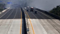 Kendaraan melintas di Tol Cibitung-Cilincing yang diselimuti asap tipis akibat kebakaran TPS ilegal.