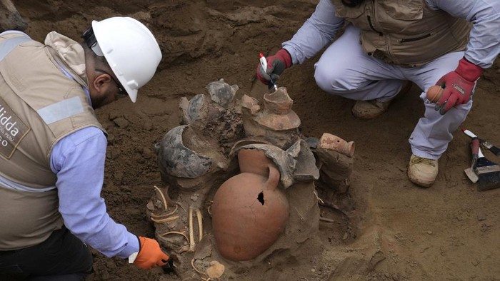 Archaeologists uncover bones and vessels discovered by city workers who were digging a natural gas line for the company Calidda in the district of Carabayllo on the outskirts of Lima, Peru, Friday, Sept. 22, 2023. Eight burial offerings from the pre-Inca Ychsma culture have been identified by archeologists so far, according to lead archeologist Jesus Bahamonde. The tube running through the site is an illegal water pipe. (AP Photo/Martin Mejia)
