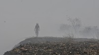 Seorang petugas pemadam kebakaran melintas diantara asap sisa kebakaran TPS (Tempat Pembuangan Sampah) ilegal samping Tol Cibitung-Cilincing, Desa Sumber Jaya, Tambun Utara, Kabupaten Bekasi, Jawa Barat, Senin (25/9/2023).   