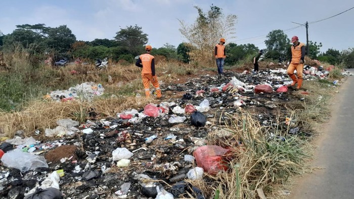 Petugas dari DLHK Depok bersihkan sampah yang dibuang warga di tepi Jalan Tanah Merah