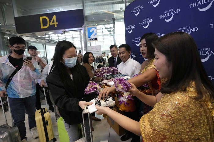 Chinese tourists dance with puppet as Chinese tourists are welcomed on the arrivals at Suvarnabhumi International Airport in Samut Prakarn province, Thailand, Monday, Sept. 25, 2023. Thailands new government granting temporary visa-free entry to Chinese tourists, signaling that the recovery of the countrys tourism industry is a top economic priority. (AP Photo/Sakchai Lalit)