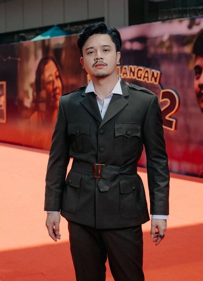 Derby Romero memakai setelan jas dan celana safari warna hijau tua, dipadu kemeja putih dan ikat pinggang. Foto: Instagram/@filmpetualangansherina