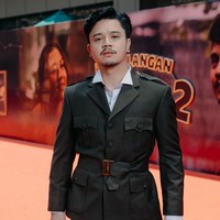 Derby Romero memakai setelan jas dan celana safari warna hijau tua, dipadu kemeja putih dan ikat pinggang. Foto: Instagram/@filmpetualangansherina