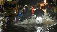 Pengendara sepeda motor melintasi jalan yang terendam banjir di Medan, Sumatera Utara.