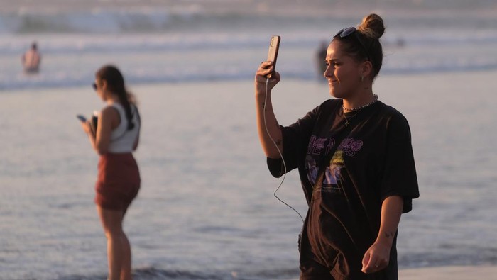 Sejumlah wisatawan membawa papan selancar berjalan menuju ke tengah laut saat berlibur di Pantai Kuta, Badung, Bali, Senin (25/9/2023). Kepala Dinas Pariwisata Provinsi Bali Tjok Bagus Pemayun mengatakan untuk retribusi sebesar Rp150 ribu kepada turis asing yang masuk Pulau Dewata diterapkan mulai Februari 2024 dan mekanismenya serta tata cara pungutan uang kepada turis asing hingga saat ini masih disusun dalam Peraturan Gubernur (Pergub) Bali. ANTARA FOTO/Nyoman Hendra Wibowo/aww.