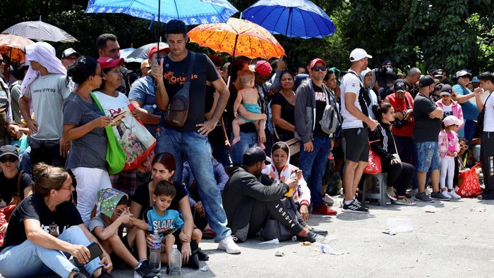 Ribuan Migran Membludak di Meksiko Minta Visa Kemanusiaan Law enforcement officers surveil, as migrants gather outside an office of Mexico's Refugee Aid Commission to obtain a humanitarian visa that allows them safe passage to continue their journey to Mexico's northern border to seek asylum in the U.S., in Tapachula, Mexico September 25, 2023. REUTERS/Jose Torres