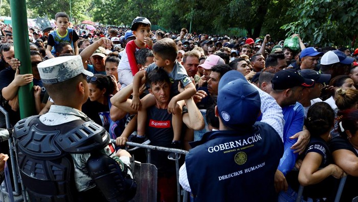 Law enforcement officers surveil, as migrants gather outside an office of Mexico's Refugee Aid Commission to obtain a humanitarian visa that allows them safe passage to continue their journey to Mexico's northern border to seek asylum in the U.S., in Tapachula, Mexico September 25, 2023. REUTERS/Jose Torres