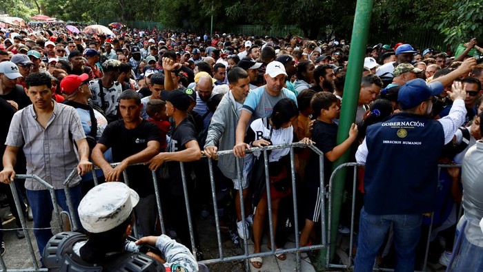 Law enforcement officers surveil, as migrants gather outside an office of Mexico's Refugee Aid Commission to obtain a humanitarian visa that allows them safe passage to continue their journey to Mexico's northern border to seek asylum in the U.S., in Tapachula, Mexico September 25, 2023. REUTERS/Jose Torres