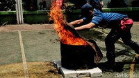 Petugas mencotohkan cara memadamkan api dengan karung goni basah.  