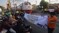 Petugas KAI Commuter bersama relawan membentangkan spanduk saat sosialisasi keselamatan perkeretaapian di perlintasan sebidang Stasiun Pondok Jati, Jakarta, Rabu (27/9/2023).