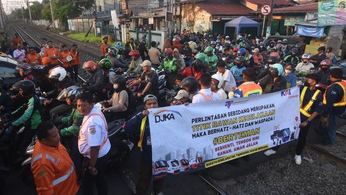 Petugas KAI Commuter bersama relawan membentangkan spanduk saat sosialisasi keselamatan perkeretaapian di perlintasan sebidang Stasiun Pondok Jati, Jakarta, Rabu (27/9/2023). Dalam rangka memperingati Hari Perhubungan Nasional, KAI Commuter melakukan kampanye keselamatan di perlintasan sebidang guna meningkatkan kesadaran para pengguna jalan raya untuk mendahulukan perjalanan kereta api yang akan melintas dan tidak menerobos palang pintu perlintasan. ANTARA FOTO/Indrianto Eko Suwarso/rwa.