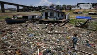 Anak laki-laki berjalan di samping rumah terapung yang terdampar di tempat yang dulunya merupakan tepi sungai Negro di Manaus, Brasil, Selasa (26/9/2023).  
