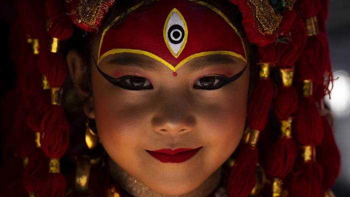 Merah Merona Anak-anak Perempuan di Nepal Saat Tradisi Kumari A young girl dressed as living goddess Kumari reacts to the camera as she waits for Kumari Puja, a worship ritual at Hanuman Dhoka, Basantapur Durbar Square, Kathmandu, Nepal, Wednesday, Sept. 27, 2023. Girls under the age of nine gathered for the tradition of worshiping young prepubescent girls as manifestations of the divine female energy. The ritual holds a strong religious significance in the Newar community that seeks divine blessings to save small girls from diseases and bad luck in the years to come. (AP Photo/Niranjan Shrestha)