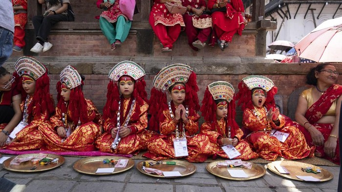 Merah Merona Anak-anak Perempuan di Nepal Saat Tradisi Kumari A young girl dressed as living goddess Kumari reacts to the camera as she waits for Kumari Puja, a worship ritual at Hanuman Dhoka, Basantapur Durbar Square, Kathmandu, Nepal, Wednesday, Sept. 27, 2023. Girls under the age of nine gathered for the tradition of worshiping young prepubescent girls as manifestations of the divine female energy. The ritual holds a strong religious significance in the Newar community that seeks divine blessings to save small girls from diseases and bad luck in the years to come. (AP Photo/Niranjan Shrestha)