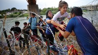 Migran dari Venezuela melewati kawat berduri setelah melintasi Rio Grande di Eagle Pass, Texas, Selasa (26/9/2023).