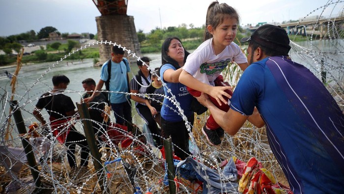 Migrants from Venezuela make their way through the razor wire after crossing the Rio Grande into the United States in Eagle Pass, Texas, U.S., September 26, 2023.   REUTERS/Brian Snyder     TPX IMAGES OF THE DAY
