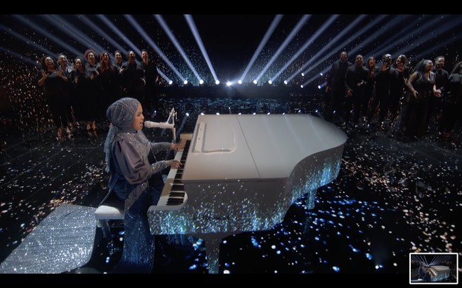 Putri Ariani tampil bling bling di final Americas Got Talent 2023 pada Selasa (26/9/2023). Dia mengenakan gaun biru berkilauan dengan ekor menyapu lantai. Detail bebatuan dan payet berkilau menghiasi hijab hingga gaun Putri Ariani. Foto: Dok. YouTube Americas Got Talent