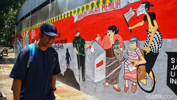 Warga berjalan di depan mural bertema Pemilu 2024 di Jl Perjuangan, Kebon Jeruk, Jakarta Barat, Kamis (28/9/2023). Pemilu serentak Pilpres, Pileg dan Pilkada akan dilakukan 14 Februari mendatang. Semua pihak berharap proses pemilu berlangsung damai dan jurdil dengan partisipasi tinggi dari masyarakat.
