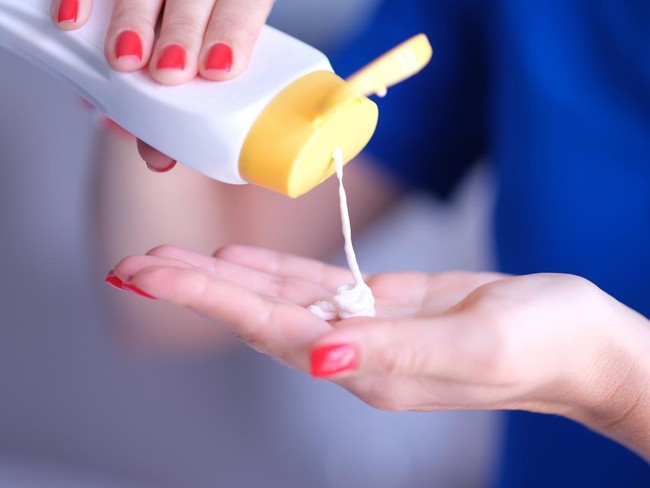 Woman pours body care lotion or sunscreen from bottle into hand. Moisturizing and protecting skin concept.