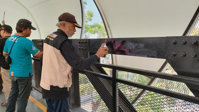 Petugas melakukan pembersihan aksi vandalisme di JPO Manahan, Jumat (29/9/2023).