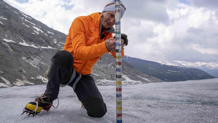 Darurat! Gletser di Swiss Hilang 10 Persen dalam Dua Tahun FILE - A team member of Swiss Federal Institute of Technology glaciologist and head of the Swiss measurement network 'Glamos', Matthias Huss, passes the Rhone Glacier covered by sheets near Goms, Switzerland, on June 16, 2023. A Swiss Academy of Sciences panel is reporting a dramatic acceleration of glacier melt in the Alpine country, which has lost 10% of its ice volume in just two years after high summer heat and low snow volumes in winter. (AP Photo/Matthias Schrader, File)