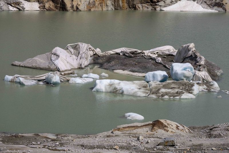 FILE - Anggota tim ahli glasiologi Institut Teknologi Federal Swiss dan kepala jaringan pengukuran Swiss 'Glamos', Matthias Huss, melewati Gletser Rhone yang tertutup lapisan dekat Goms, Swiss, pada 16 Juni 2023. Panel Akademi Ilmu Pengetahuan Swiss melaporkan percepatan pencairan gletser yang dramatis di negara pegunungan Alpen, yang telah kehilangan 10% volume esnya hanya dalam dua tahun setelah panas terik di musim panas dan sedikit hujan salju di musim dingin.  (Foto AP/Mathias Schrader, File)