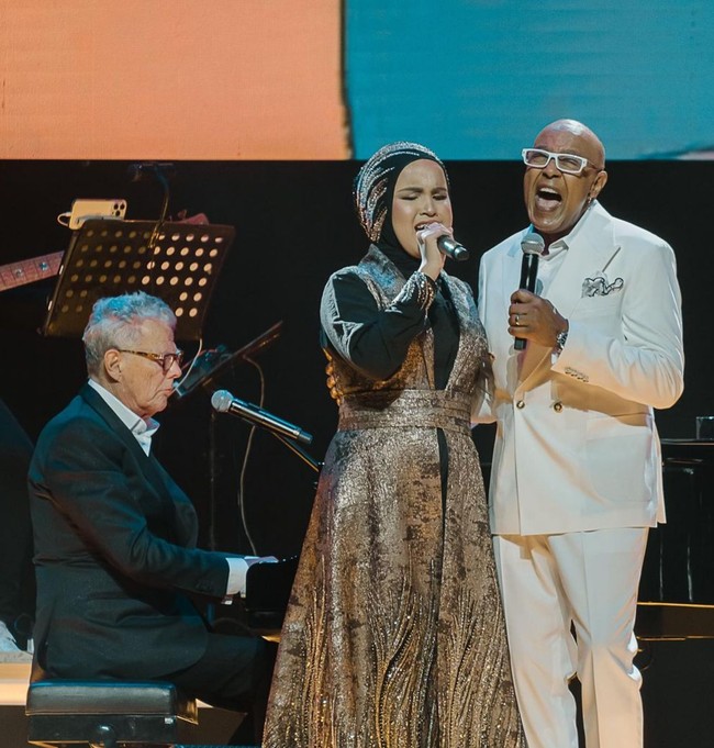 Sembari menunggu tampil di semifinal America’s Got Talent 2023, Putri mengisi waktu dengan berkarya dan bernyanyi di berbagai acara. Bahkan dia menjadi salah satu talent di konser David Foster dan berduet dengan penyanyi senior Peabo Bryson. Penampilannya cantik dan modest berbalut gaun hitam yang dipadu vest emas metalik karya Tiffany Liem. Foto: Instagram/@arianinismaputri