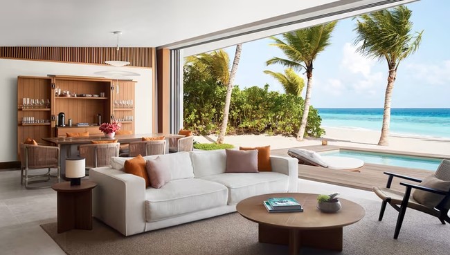 Tampak tersedia ruang makan dan sofa untuk bersantai menikmati pantai Maldives yang indah. Tepat di sebrang ruang keluarga terdapat kolam renang dan kursi santai dengan dekorasi serba kayu. Dok. Ritz Carlton